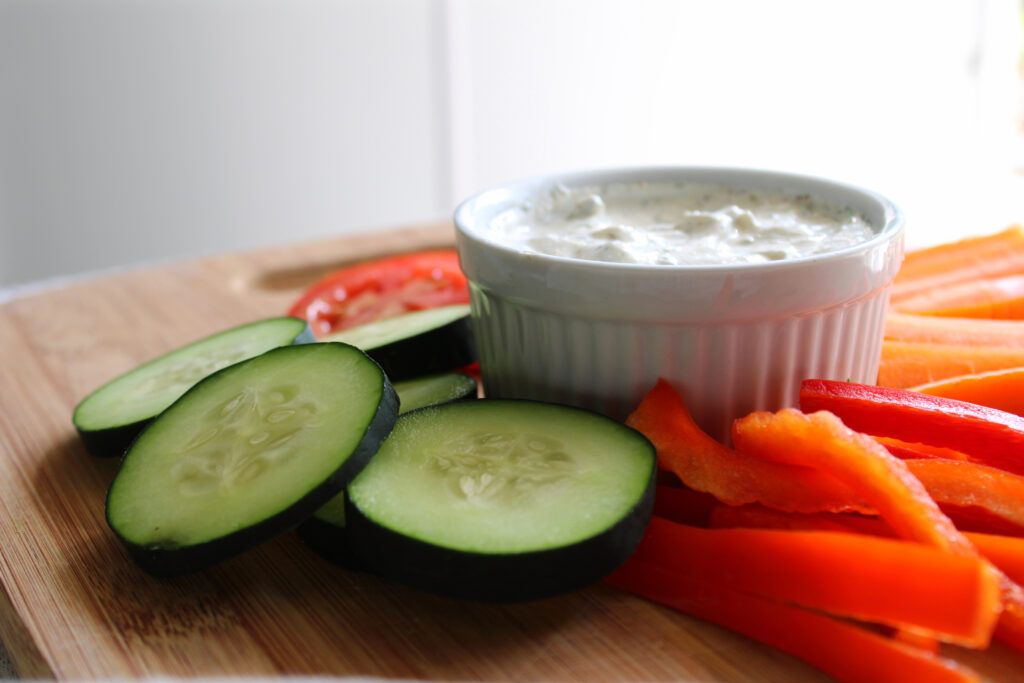 Ranch dip on a cutting board with vegetables.