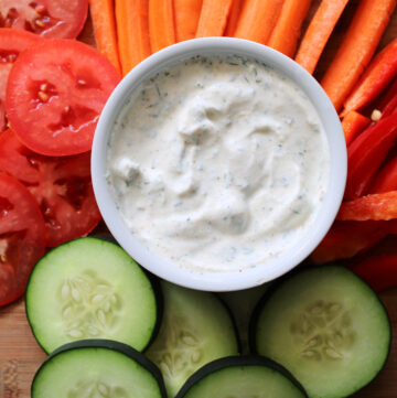 Ranch dip with vegetables on a cutting board.