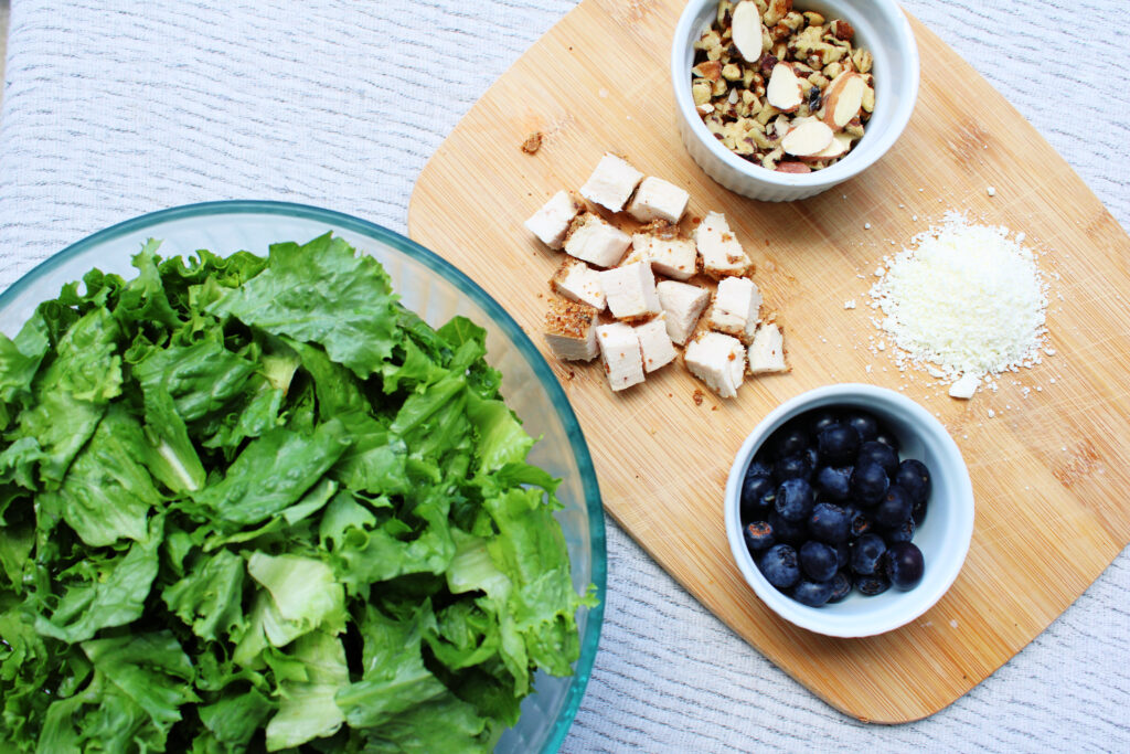 Simple Blueberry and Feta Salad with oven roasted chicken ingredients in bowls on a cutting board.