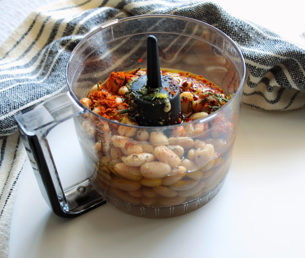 Spicy white bean dip ingredients in a food processor.