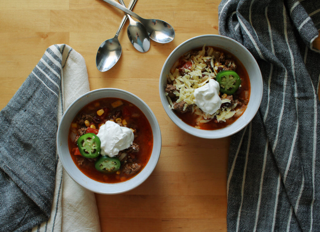 Slow cooker cowboy chili in white bowls.