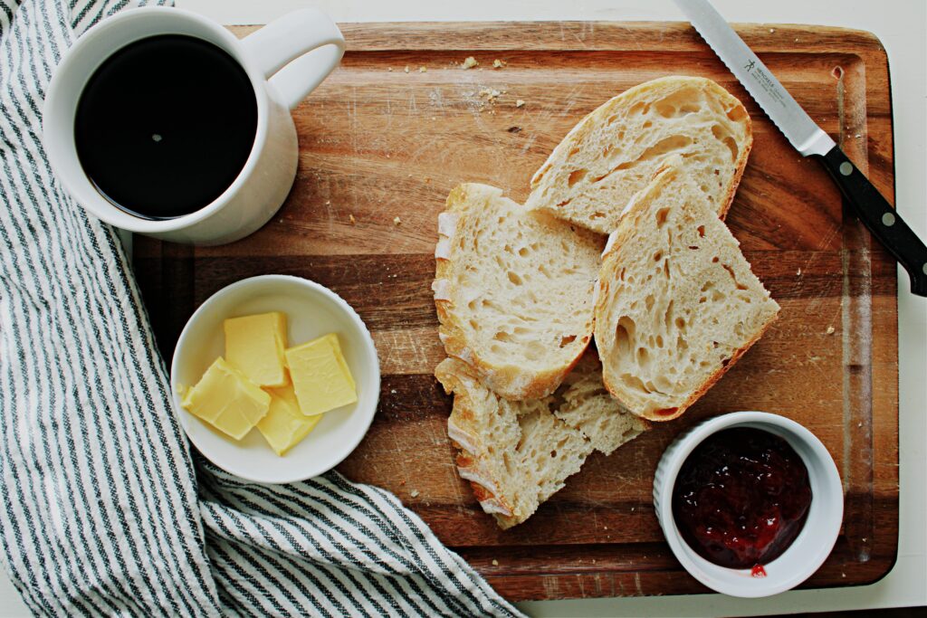 Sliced same day sourdough with jam and butter on a cutting board.