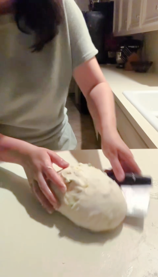 shaping the fall apple cinnamon sourdough with a bench scraper.