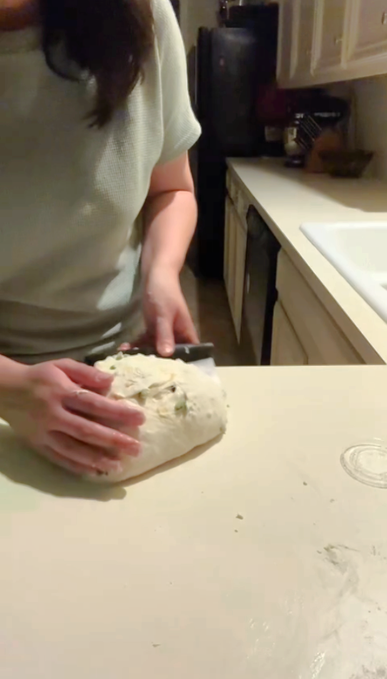 shaping the fall apple cinnamon sourdough with a bench scraper.