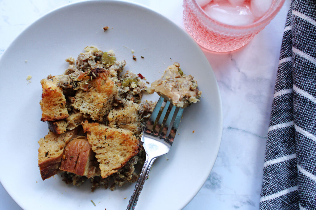 Slice of easy sourdough stuffing on a white plate with a drink and napkin.