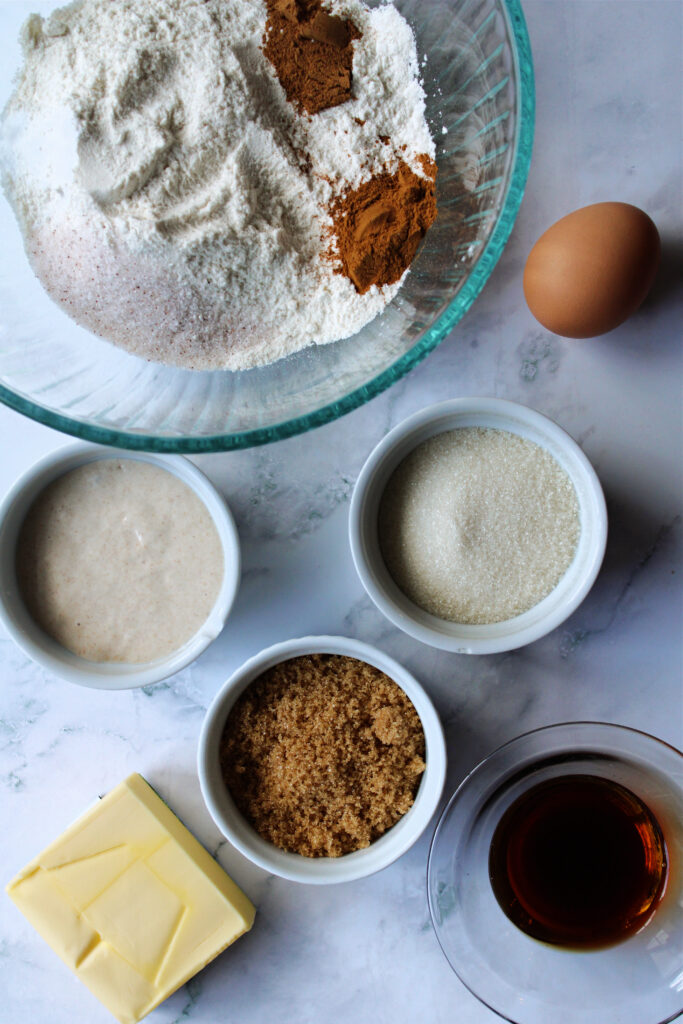 Bowls with flour, starter, sugar, and other sourdough fall baking essentials.