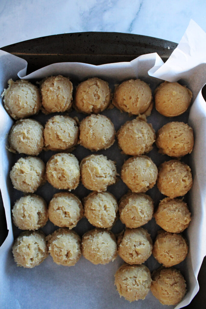 Cookie dough balls in a baking pan on the counter.