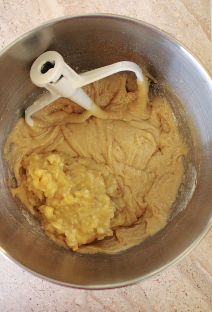 Banana bread batter with mashed bananas in a mixing bowl.