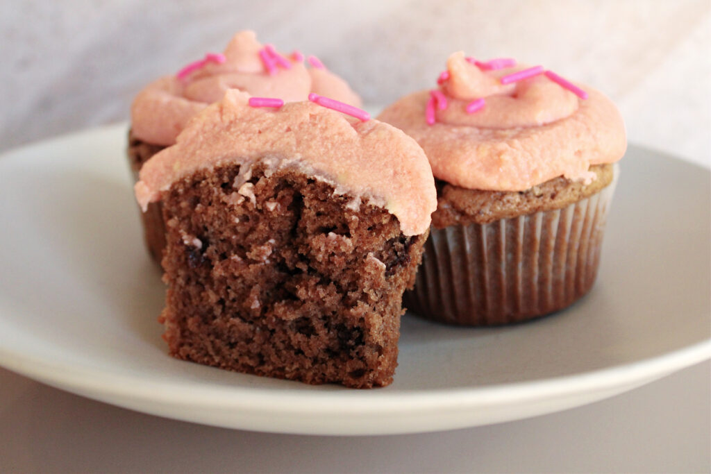 Frosted sourdough chocolate chip cupcakes served on a plate.