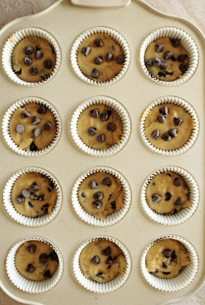 Sourdough chocolate chip muffin batter in a muffin tin.