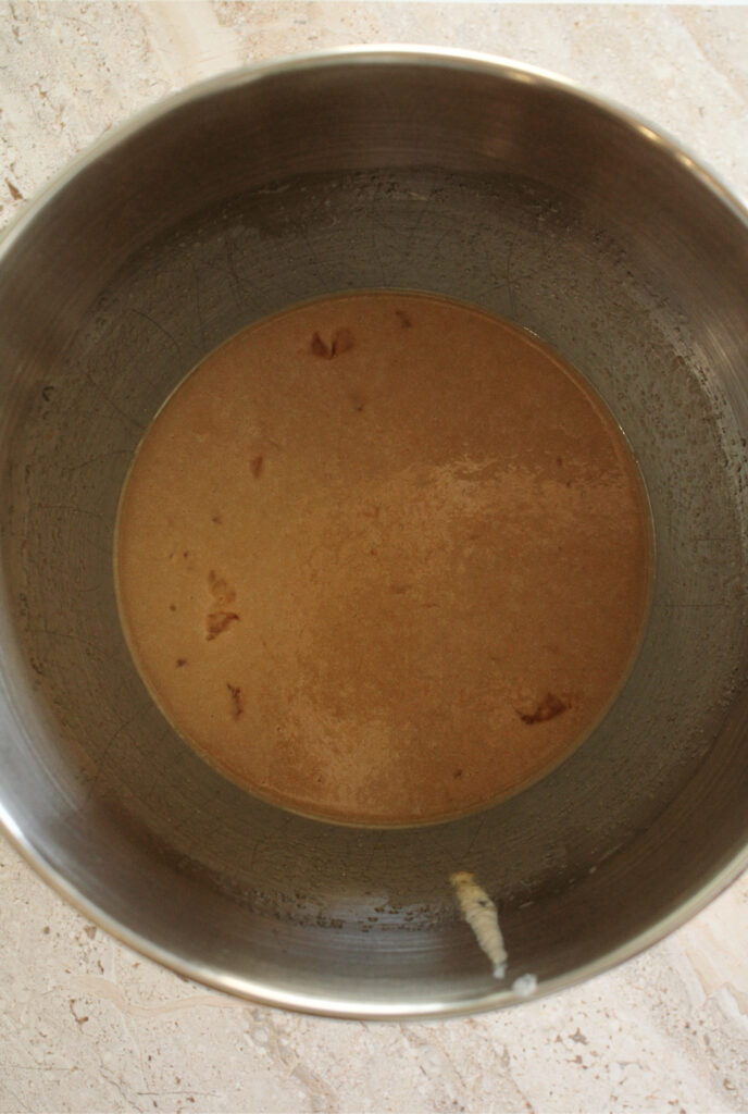 Wet ingredients for sourdough chocolate chip muffins are in a mixing bowl on the counter.