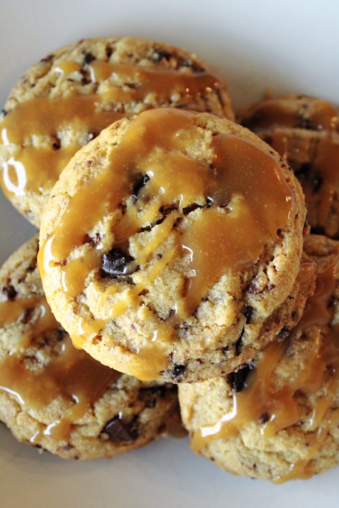 Peanut butter cup cookies with salted caramel cooling on top.