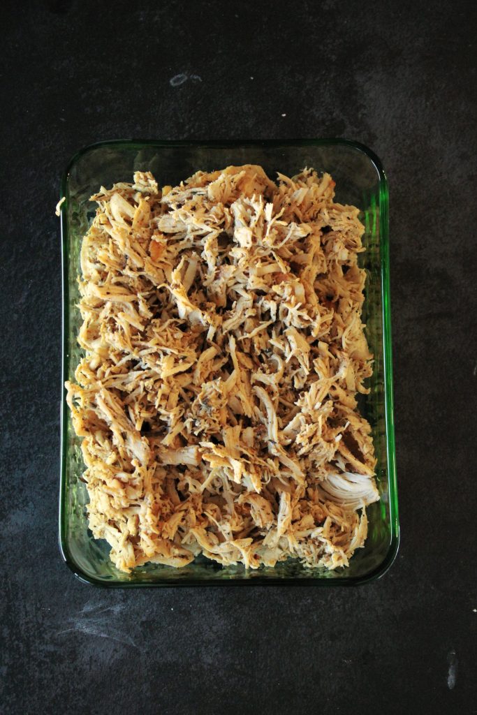 Shredded chicken for the butternut squash and chicken soup in an container cooling on the counter.