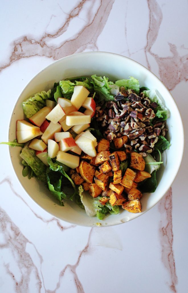 Autumn Harvest Salad with Apples and Sweet Potatoes and pecans in a bowl on the counter.
