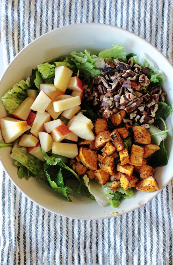 Autumn Harvest Salad with Apples and Sweet Potatoes in a bowl on top of a tea towel.