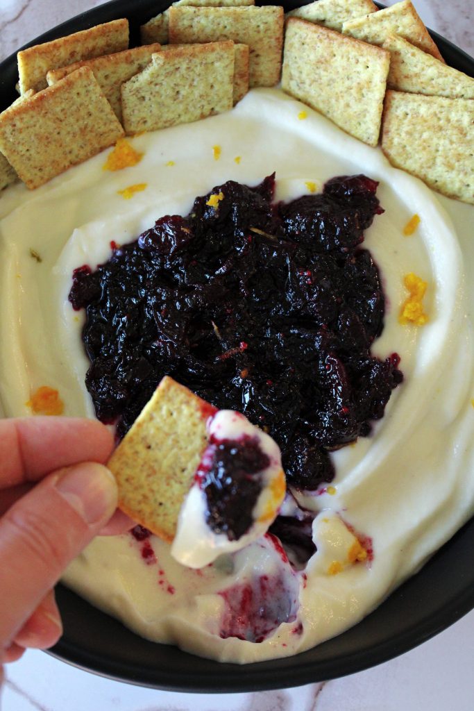 Cracker dipped in Holiday Cranberry Orange Whipped Ricotta.