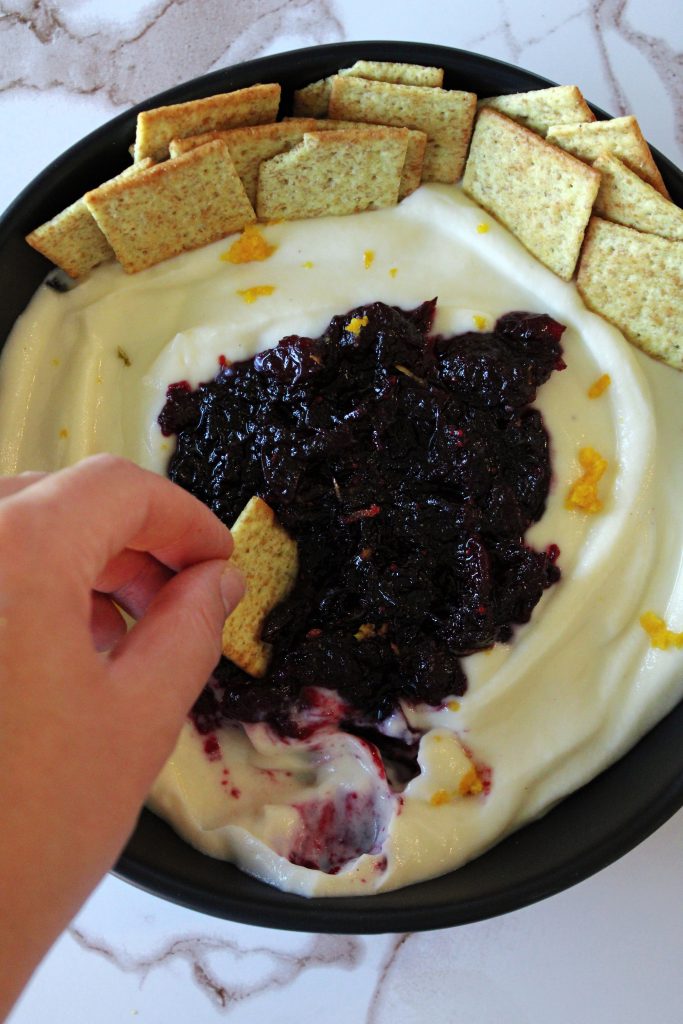 Dipping a cracker into the holiday cranberry orange whipped ricotta.