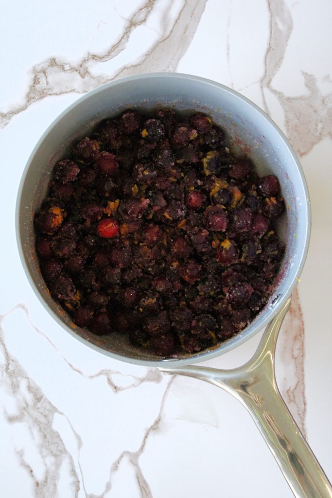 Cranberry jam and orange zest in a sauce pot ready to simmer.